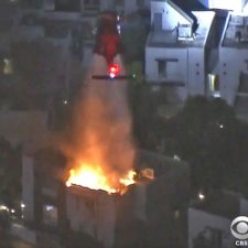 Night flying helicopter drops water on structure fire near World Series game